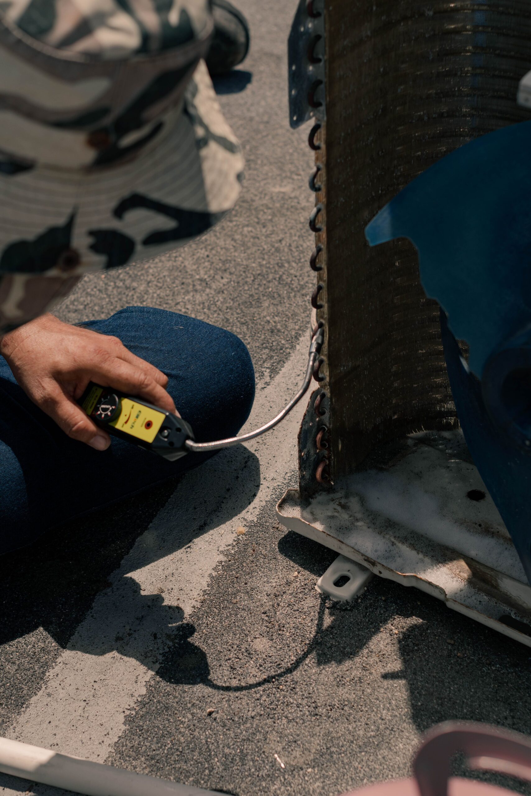 HVAC technician checking refrigerant levels on an outdoor AC unit in the heat