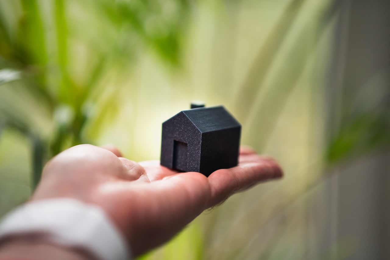 A miniature house model held in an open hand, showing the coverage choice for your home